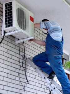 picture of technician working on the installation of the outside portion of the airconditioning unit orig 225x300
